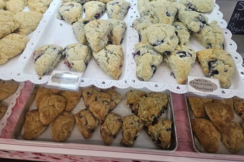 Trays of blueberry and cherry berry scones with handwritten labels in the bakery case